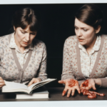 Two women examine animal organs on a table, suggesting haruspicy.